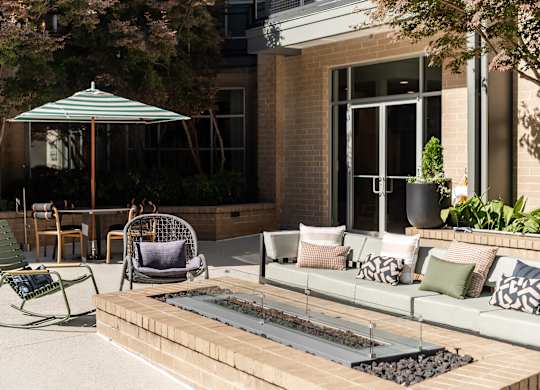 A patio with a couch, chairs, and an umbrella.