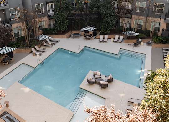 A large outdoor swimming pool surrounded by lounge chairs and umbrellas.