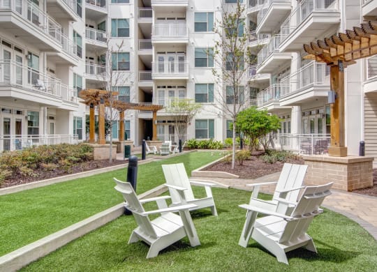 chairs and a firepit on the grassy courtyard of an apartment complex