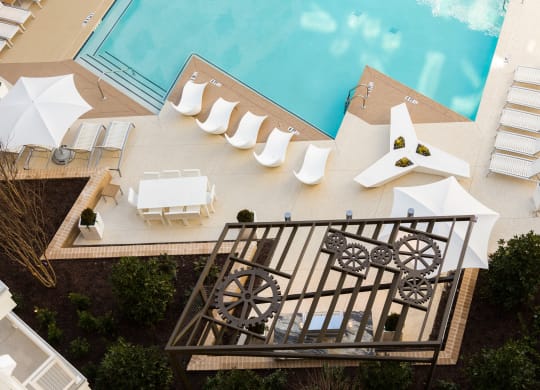 arial view of a swimming pool with white lounge chairs and umbrellas
