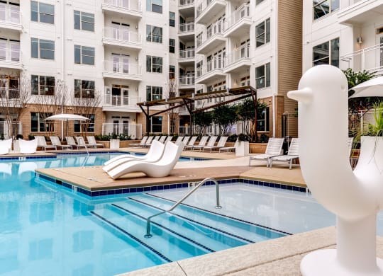 a swimming pool with a white duck statue in front of an apartment building