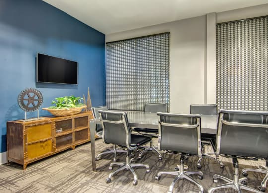 a conference room with a table and chairs and a tv on the wall