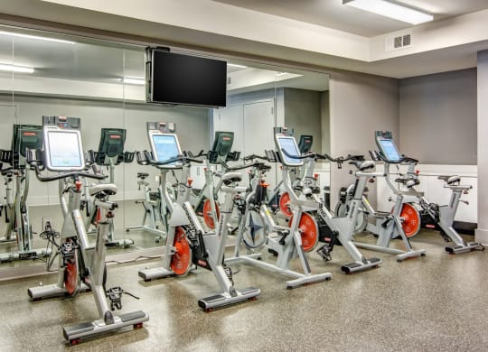 a room filled with lots of cardio equipment and a flat screen tv