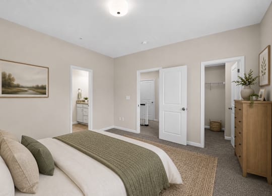 Spacious townhome bedroom with neutral walls, attached bathroom, and walk-in closet access.