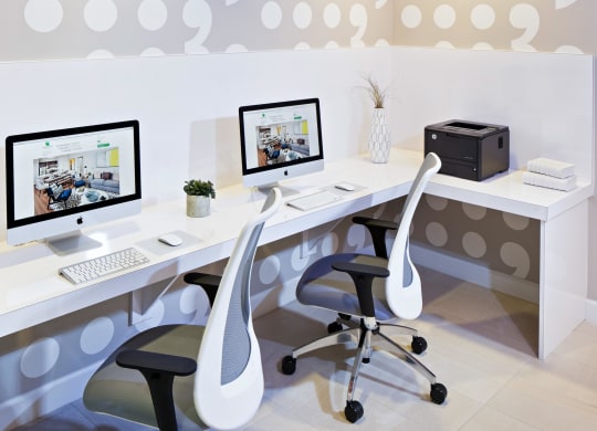 a white office with two computer monitors and two chairs