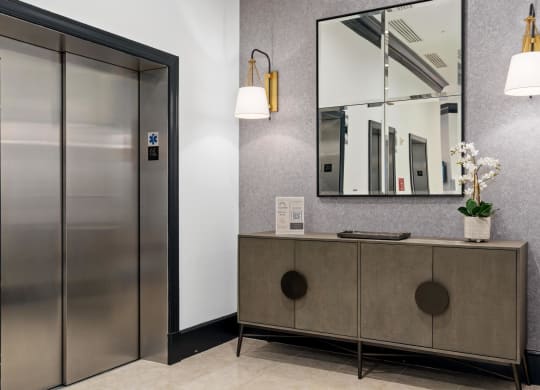 a lobby with a cabinet and a mirror and a elevator