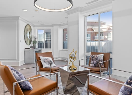 a living room with leather chairs and a chandelier