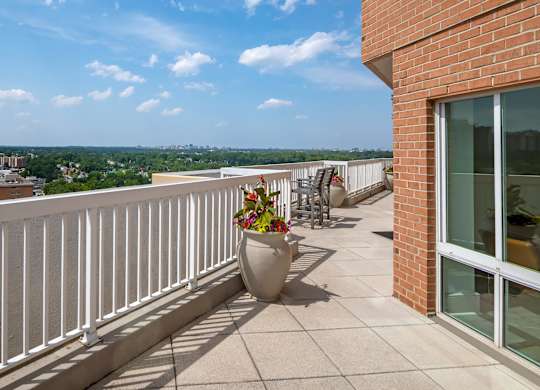 A balcony with a white railing and a large planter.