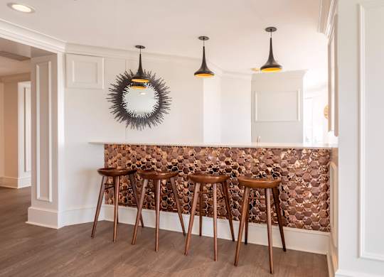 A bar with three stools and a mirror on the wall.