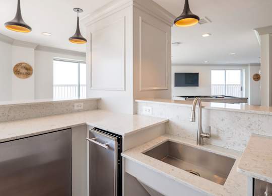 A modern kitchen with a stainless steel dishwasher and a sink with a marble countertop.