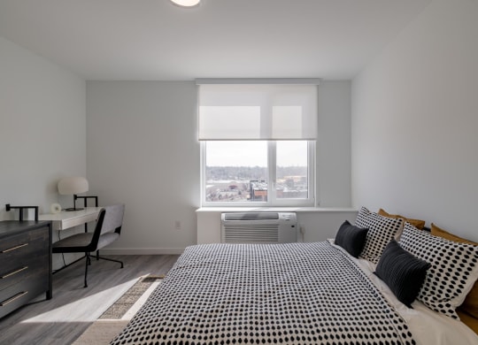 a bedroom with a bed and a desk and a window