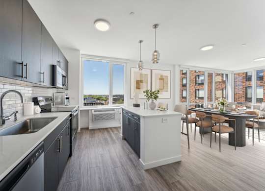 A modern kitchen with dark grey cabinets and a white countertop.