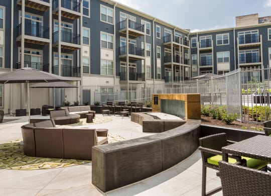 a courtyard with furniture and a fire pit in front of an apartment building