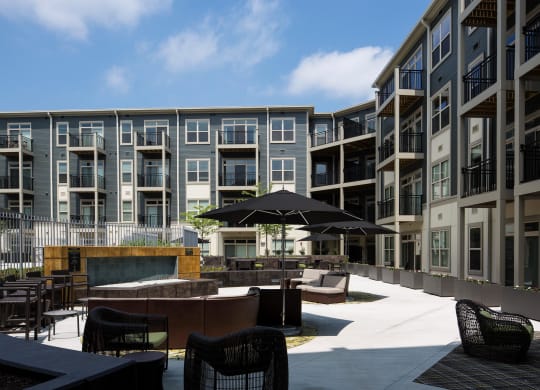 a courtyard with tables and chairs and an umbrella in front of an apartment building