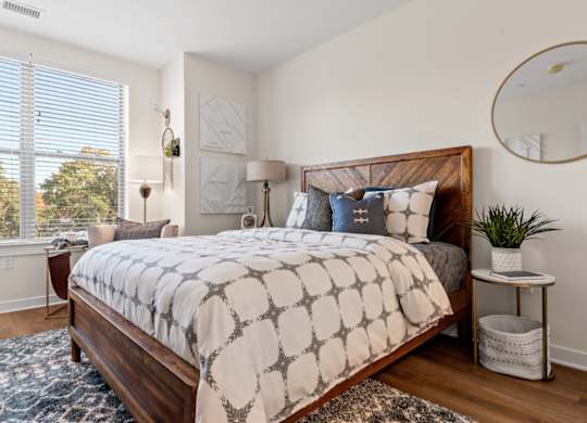 A bedroom with a large bed and a window with blinds.