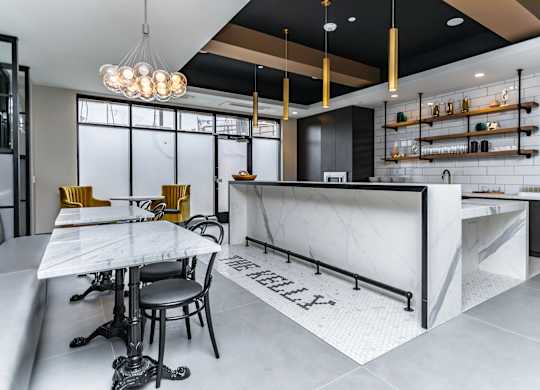 A modern kitchen with a marble island and bar stools.