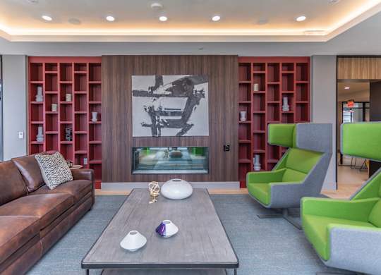 A living room with a brown leather couch, a grey armchair, a coffee table, and a large painting on the wall.