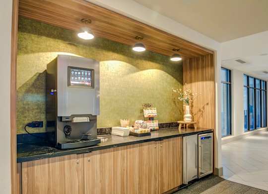 A coffee machine is on a counter with a digital menu board above it.