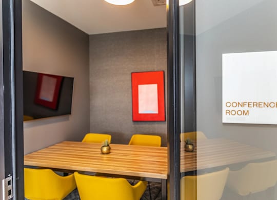 A conference room with a wooden table and yellow chairs.