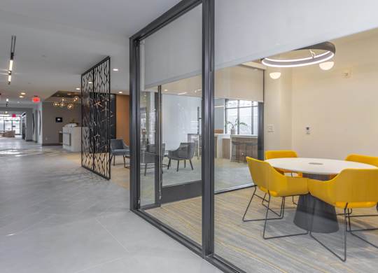 A conference room with a glass door and a table with yellow chairs.