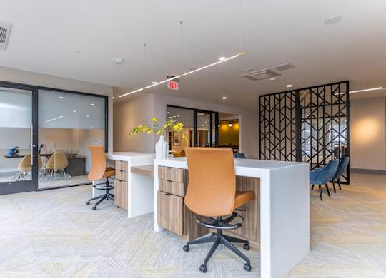 A modern office space with a white desk and orange chairs.