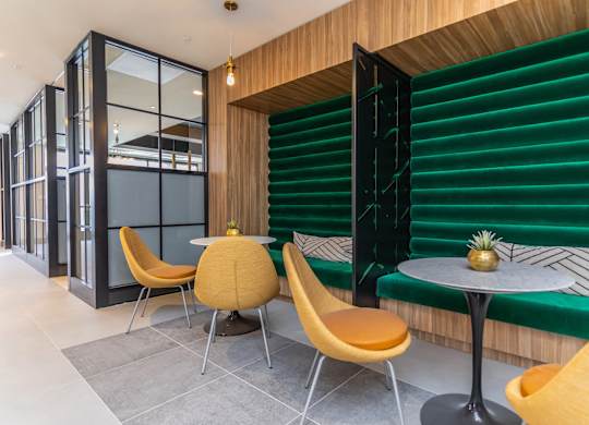 A modern dining area with a green bench and yellow chairs.