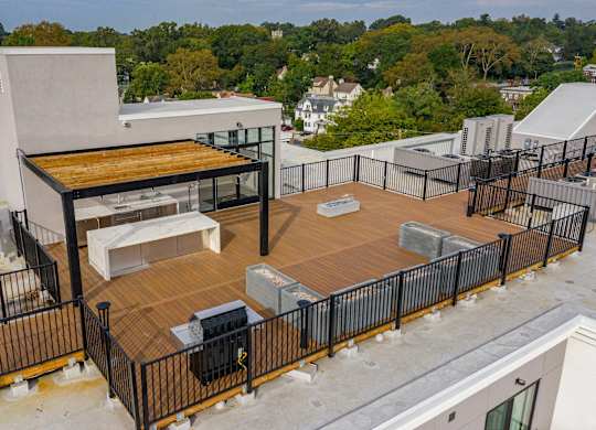 A rooftop patio with a grill and seating area.