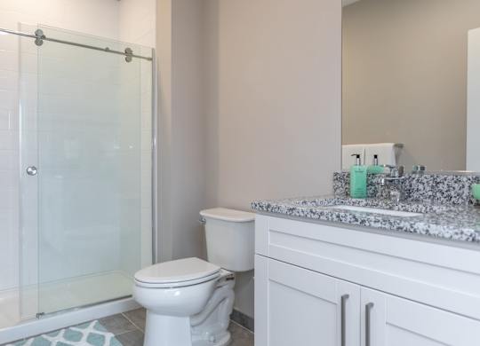 A white toilet sits next to a glass shower door in a bathroom.