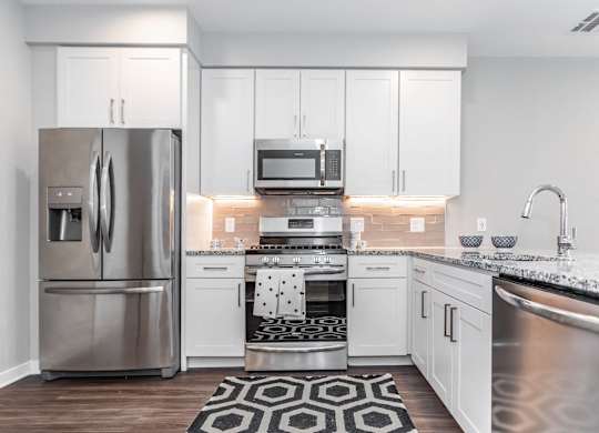 A modern kitchen with a stainless steel refrigerator and white cabinets.
