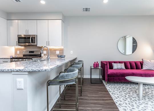 A modern kitchen with a pink couch and a marble countertop.