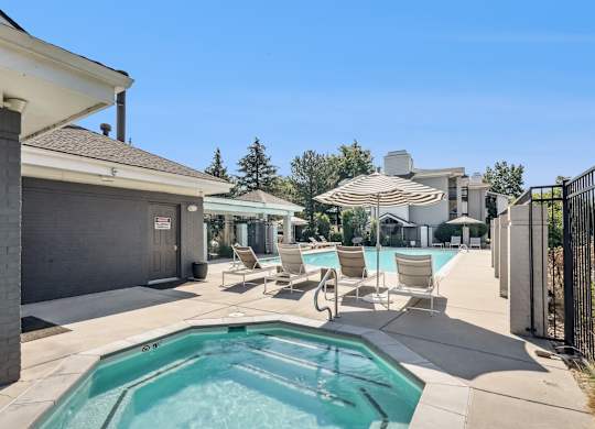 A pool with chairs and an umbrella in front of a house at The Magwood in Boulder, Colorado.