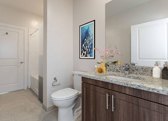 A bathroom with a toilet, sink, and a painting on the wall.