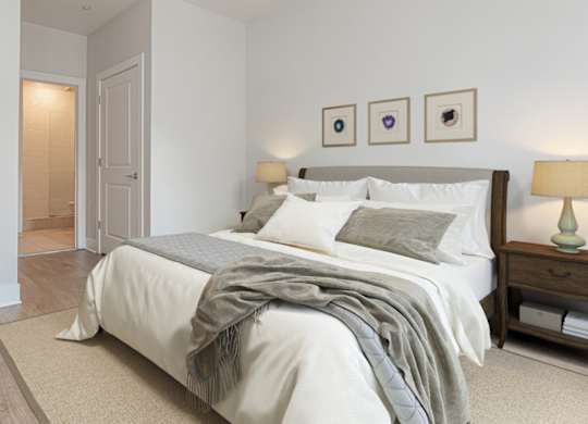 A bedroom with a bed, nightstand, and lamp.