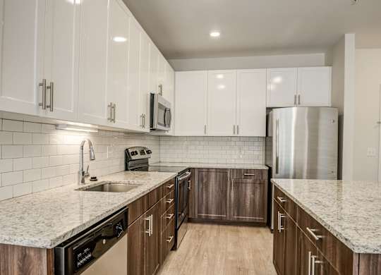 A kitchen with white cabinets and a granite countertop.