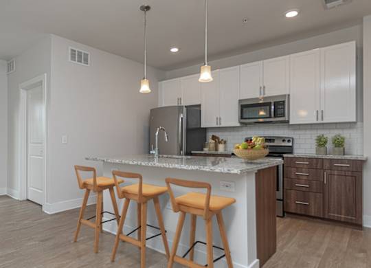 A kitchen with white cabinets and a bar area with stools.