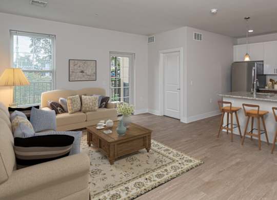 A well-lit, modern kitchen with a breakfast bar and a living room area with a sofa and coffee table.