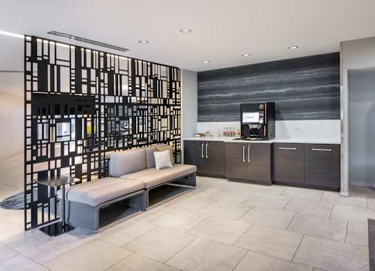Vantage Mosaic hospitality bar with a beverage machine, dark cabinetry, counter space, bench seating and black screen divider.