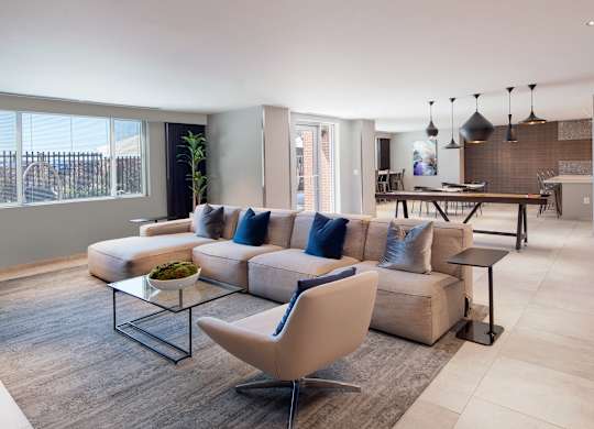 Wide view of The Lounge at Vantage Mosaic with sectional seating, dining tables, an entertaining kitchen and shuffleboard.