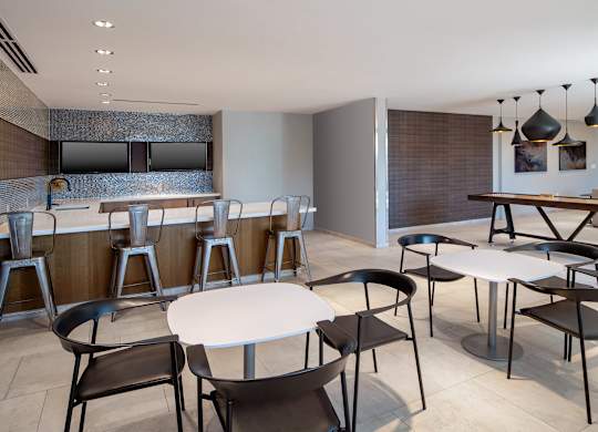 Entertaining kitchen in The Lounge with an island, bar seating, round dining tables and a shuffleboard table.