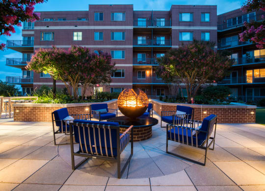 an outdoor patio with chairs and a fire pit at dusk