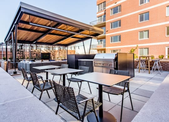 a patio with tables and chairs and a barbecue grill