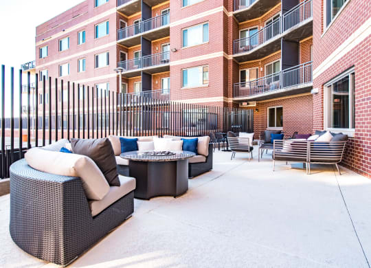 a patio with furniture and a fire pit in front of an apartment building