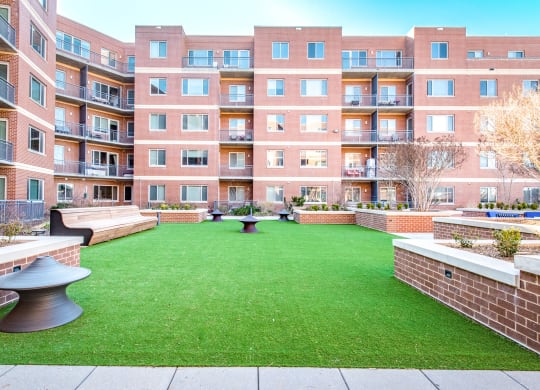 a courtyard with a green lawn in front of an apartment building