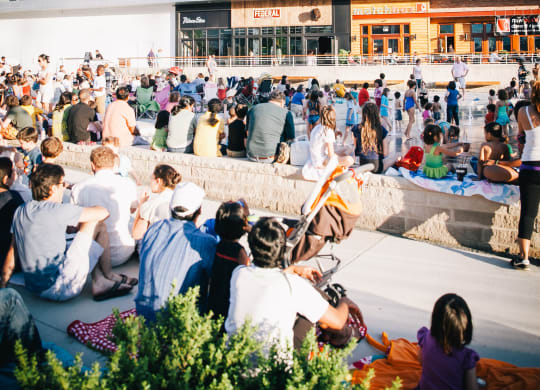 a crowd of people sitting outside of a building watching a movie