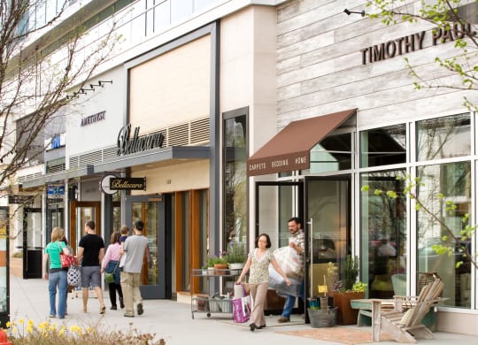 people walking down a sidewalk in front of a shopping mall