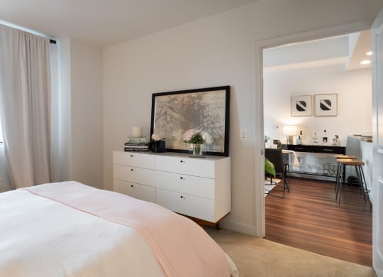 a bedroom with a white bed and a dresser and a window