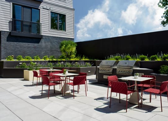 an outdoor patio with tables and chairs and barbecue grills