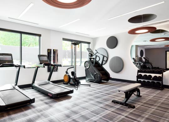 a gym with treadmills and other exercise equipment in a large room with windows