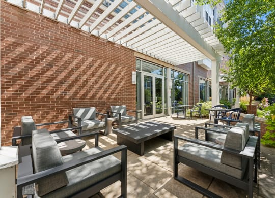 a patio with tables and chairs and a brick wall