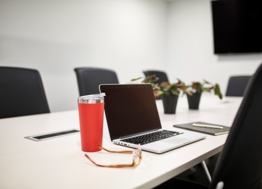 a conference room with a laptop and a drink on the table